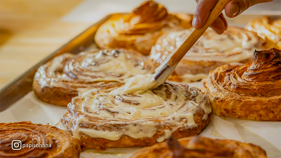 Icing being brushed onto fresh cinnamon rolls at Papi's Ohana in Lahaina, Maui.