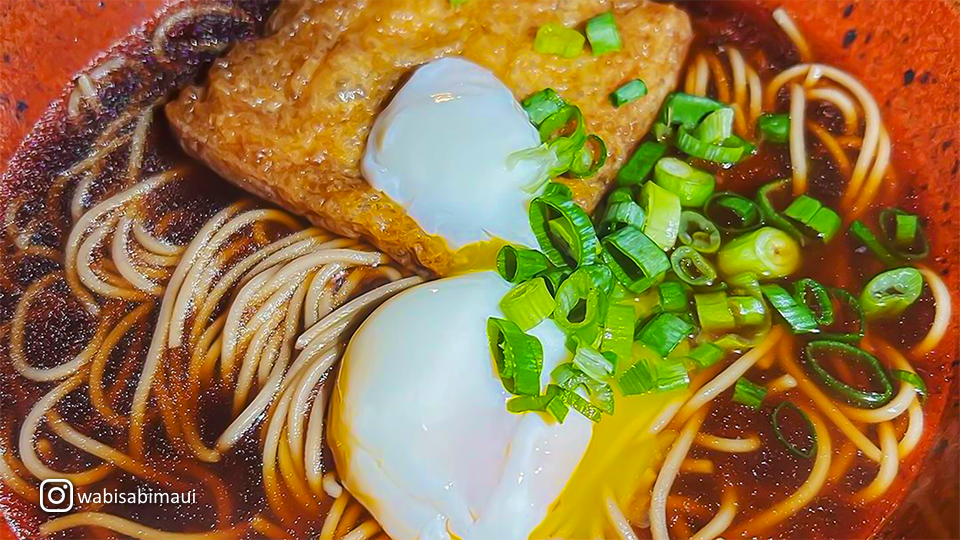 Close-up of freshly prepared soba noodles at Wabisabi Soba & Sushi, served with a light dipping sauce and garnished with green onions.